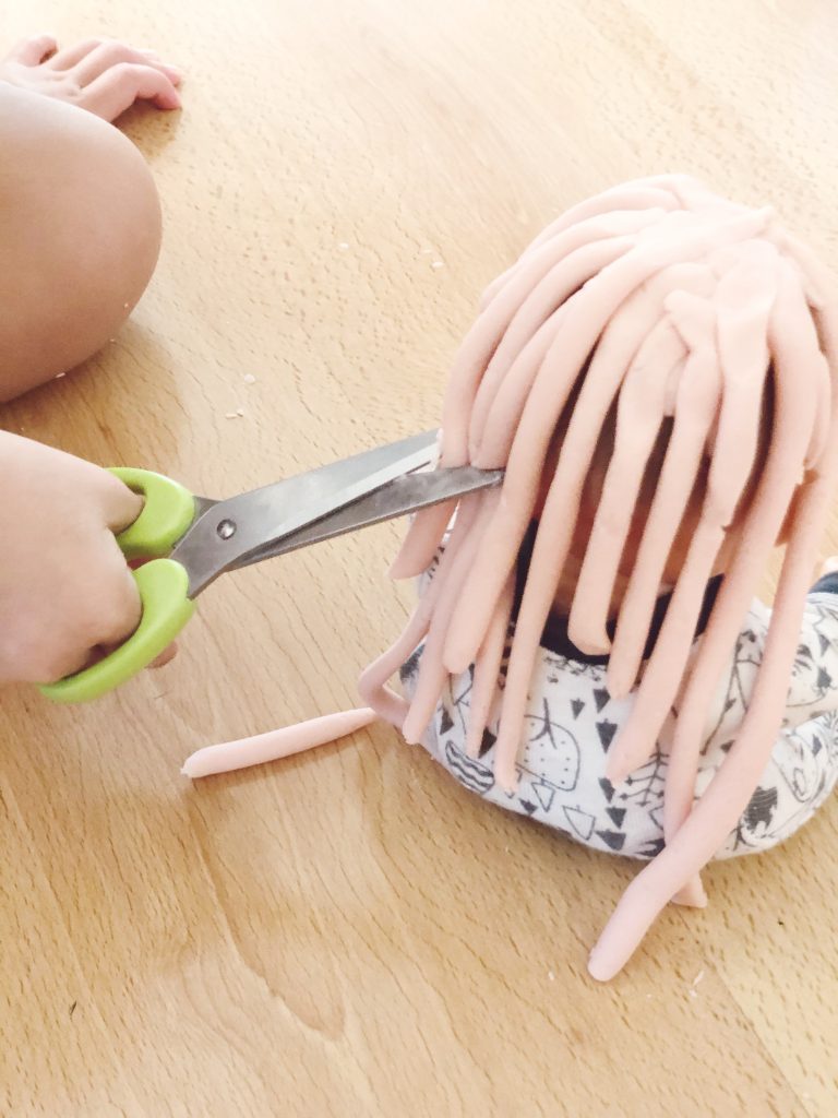 Scissor cutting skills practice activity for toddlers and preschool with playdough hair on a doll